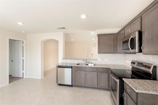 kitchen with sink, light stone countertops, stainless steel appliances, and light tile patterned floors