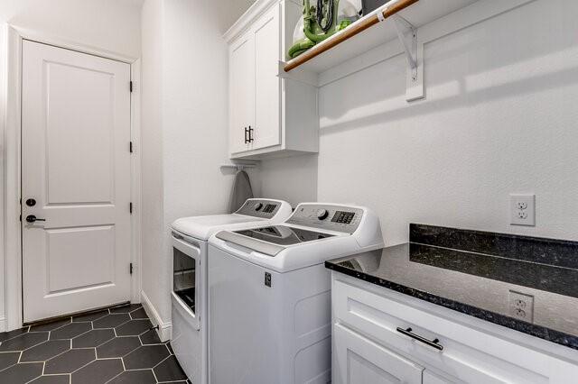 washroom featuring cabinets, washing machine and dryer, and dark tile patterned flooring