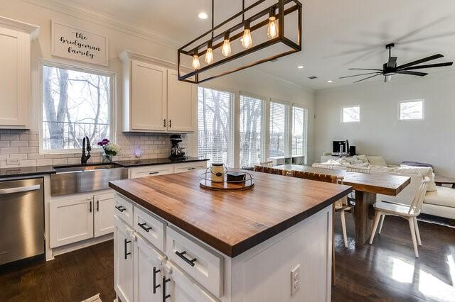 kitchen featuring white cabinetry, sink, wood counters, stainless steel dishwasher, and a kitchen island