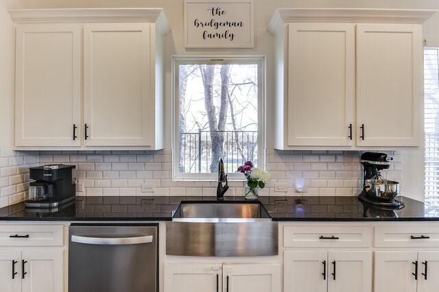 kitchen with stainless steel dishwasher, sink, white cabinets, and backsplash