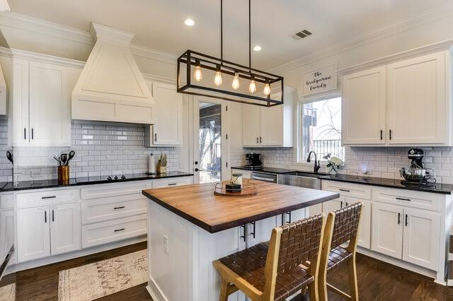 kitchen with white cabinetry, butcher block countertops, pendant lighting, a kitchen island, and custom range hood