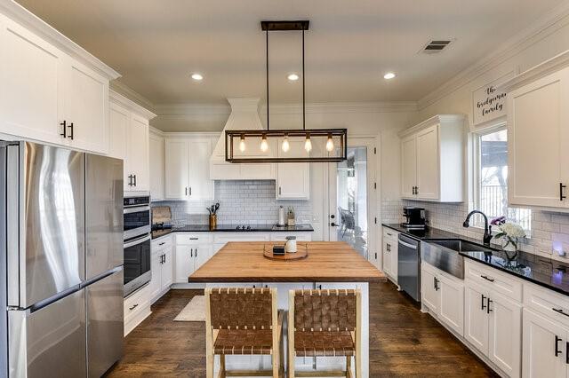 kitchen with white cabinetry, a center island, sink, hanging light fixtures, and stainless steel appliances