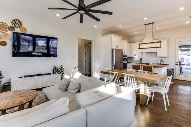 living room featuring ceiling fan, dark hardwood / wood-style floors, and crown molding