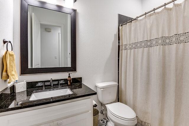 bathroom with a shower with shower curtain, vanity, and toilet