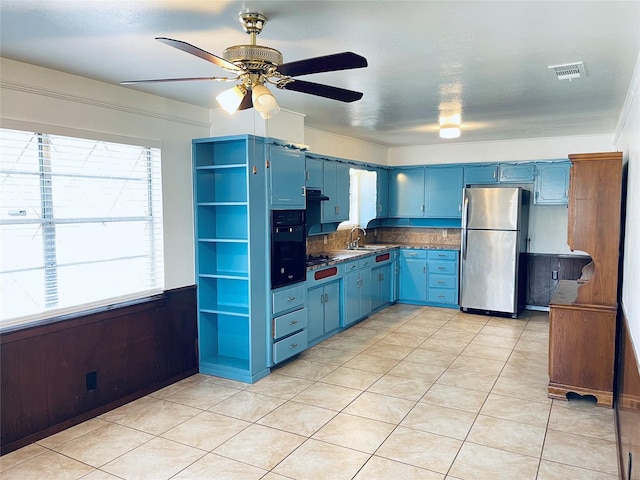 kitchen with sink, stainless steel fridge, black oven, tasteful backsplash, and blue cabinets