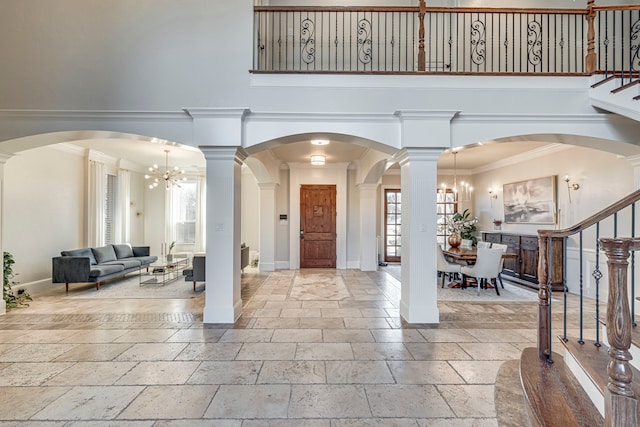 entrance foyer with an inviting chandelier, a towering ceiling, and decorative columns