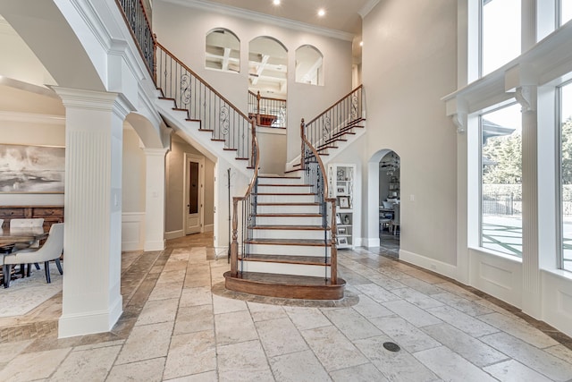 entrance foyer with ornamental molding, coffered ceiling, decorative columns, and a high ceiling