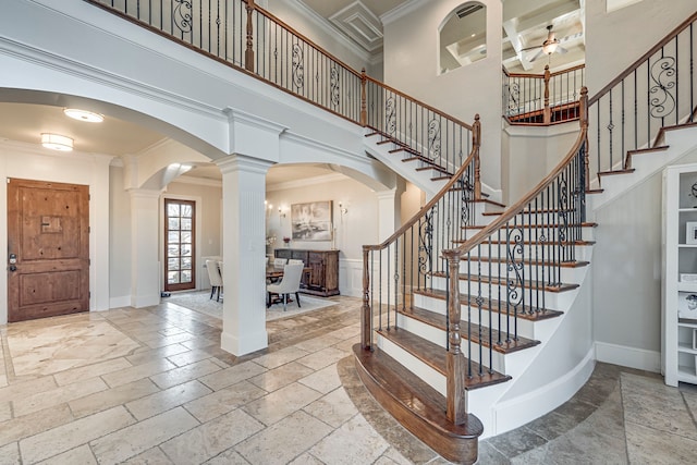 entryway featuring decorative columns, ornamental molding, a towering ceiling, and ceiling fan