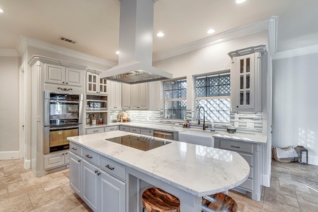 kitchen featuring sink, a breakfast bar area, island range hood, black electric cooktop, and stainless steel double oven