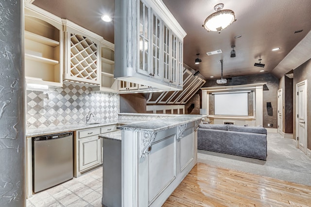 kitchen with light stone countertops, a kitchen island, decorative backsplash, vaulted ceiling, and stainless steel dishwasher