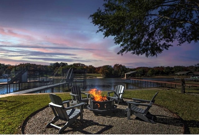 yard at dusk with a water view and a fire pit