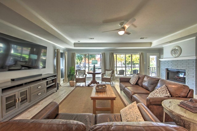 living room with ceiling fan, plenty of natural light, light hardwood / wood-style floors, and a brick fireplace