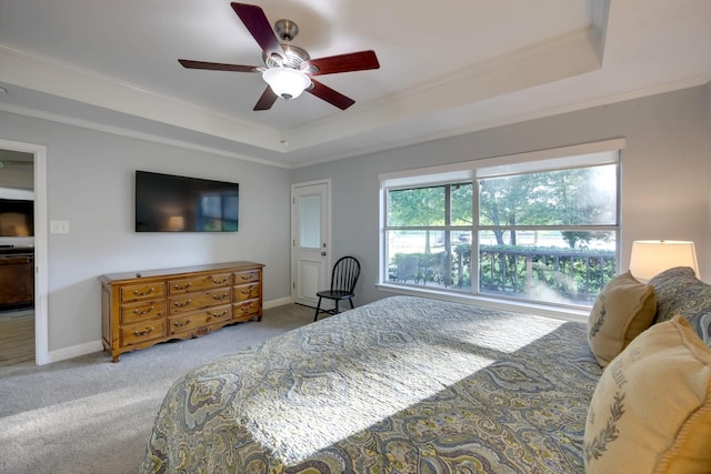 carpeted bedroom with ceiling fan, ornamental molding, and a tray ceiling