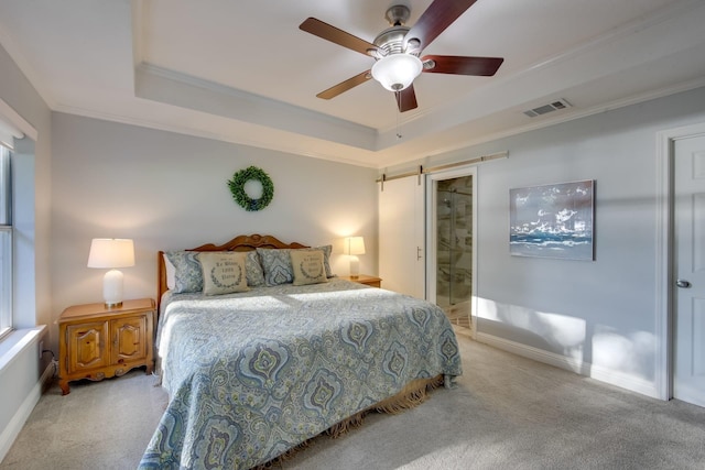 carpeted bedroom featuring ensuite bath, ornamental molding, a raised ceiling, ceiling fan, and a barn door