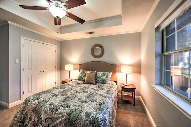 bedroom featuring a tray ceiling, ceiling fan, a closet, and dark carpet