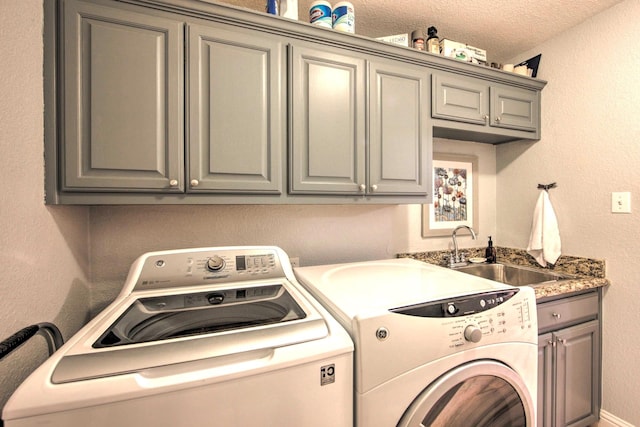 clothes washing area with sink, cabinets, separate washer and dryer, and a textured ceiling