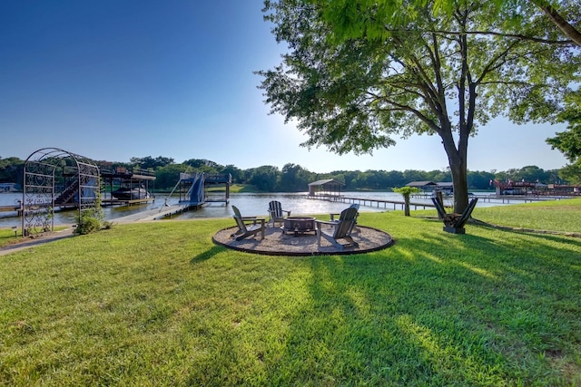 view of yard with a boat dock, a water view, and an outdoor fire pit