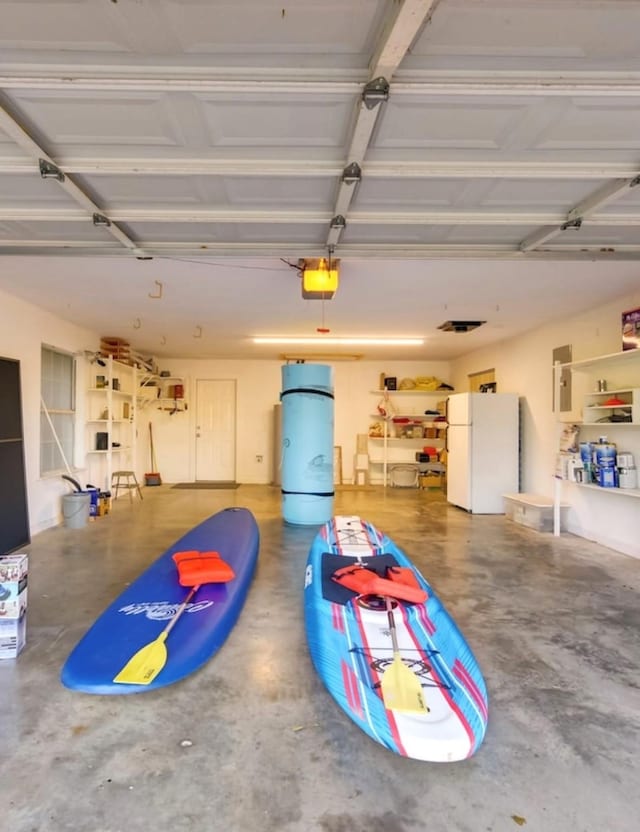 garage featuring electric panel, white fridge, and a garage door opener