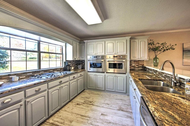 kitchen with backsplash, stainless steel appliances, gray cabinetry, and sink