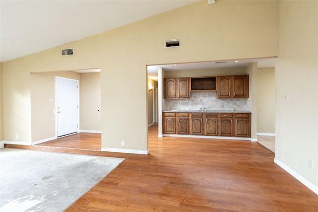 unfurnished living room featuring sink, vaulted ceiling, and hardwood / wood-style flooring