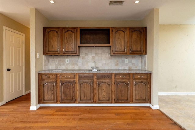 kitchen with decorative backsplash, light wood-type flooring, and sink