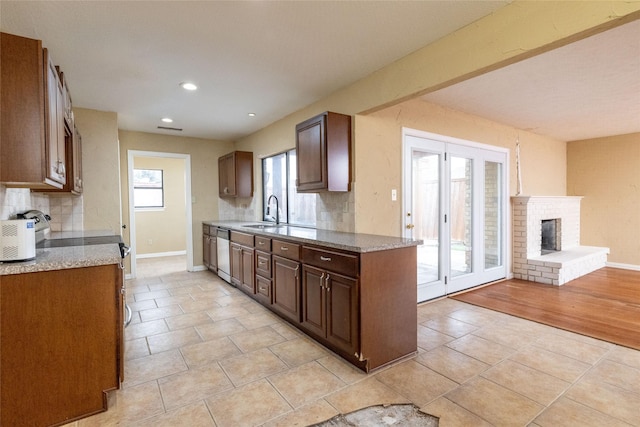 kitchen featuring dishwasher, backsplash, a brick fireplace, electric range, and light tile patterned floors