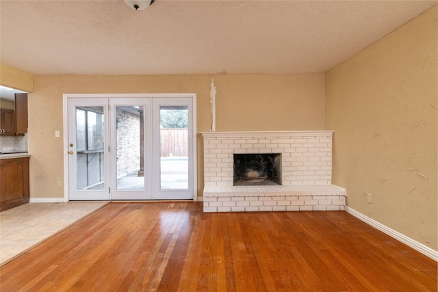 unfurnished living room with a fireplace, wood-type flooring, and a textured ceiling