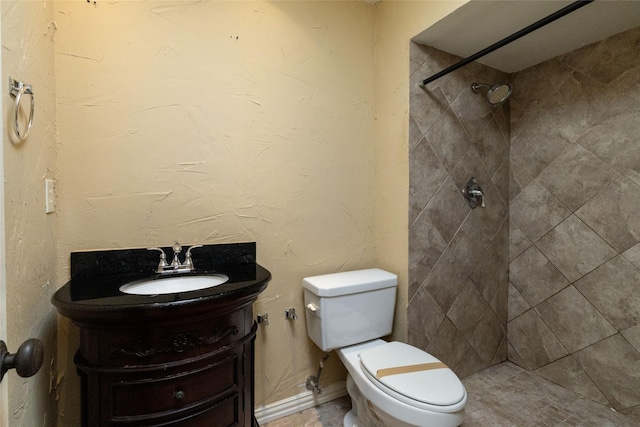 bathroom featuring a tile shower, vanity, and toilet