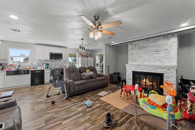 living room featuring a fireplace, ceiling fan, a healthy amount of sunlight, and sink