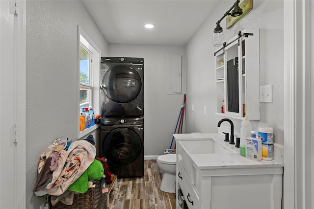 bathroom with hardwood / wood-style floors, vanity, toilet, and stacked washer and clothes dryer