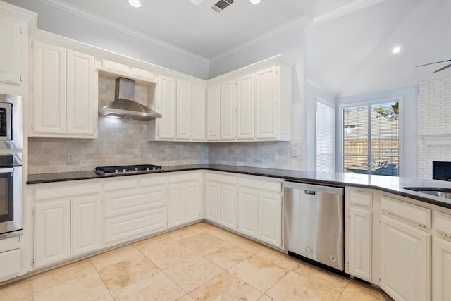 kitchen featuring appliances with stainless steel finishes, white cabinetry, wall chimney range hood, and decorative backsplash