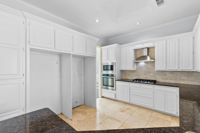 kitchen with white cabinets, appliances with stainless steel finishes, wall chimney range hood, and backsplash