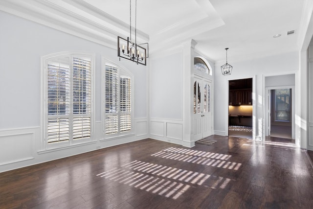 unfurnished dining area with an inviting chandelier, ornamental molding, a tray ceiling, and dark hardwood / wood-style floors