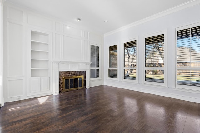 unfurnished living room with dark hardwood / wood-style floors, crown molding, built in shelves, and a fireplace