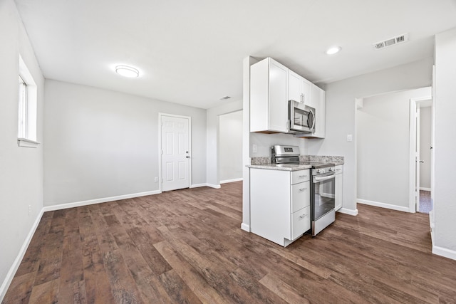 kitchen with appliances with stainless steel finishes, dark hardwood / wood-style floors, white cabinetry, and light stone counters