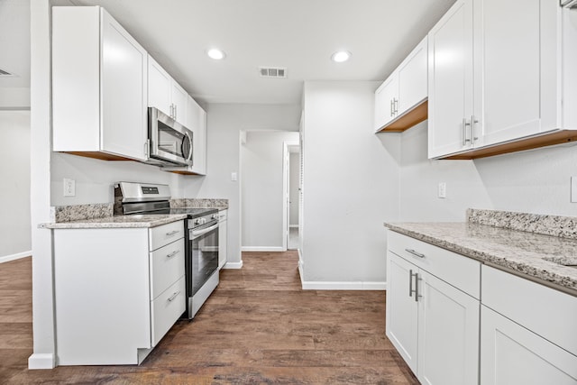 kitchen with white cabinets, light stone countertops, dark wood-type flooring, and appliances with stainless steel finishes