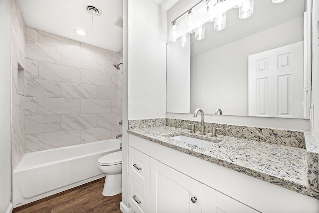 full bathroom with hardwood / wood-style flooring, toilet, vanity, and tiled shower / bath