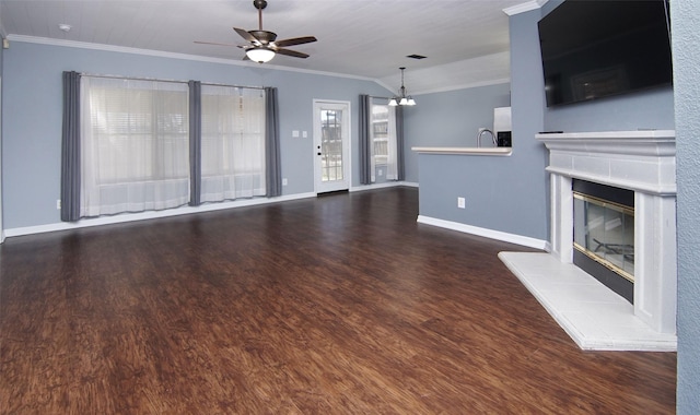 unfurnished living room with ceiling fan with notable chandelier, ornamental molding, a fireplace, and dark wood-type flooring