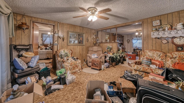 misc room with a textured ceiling, carpet floors, ceiling fan, and wooden walls