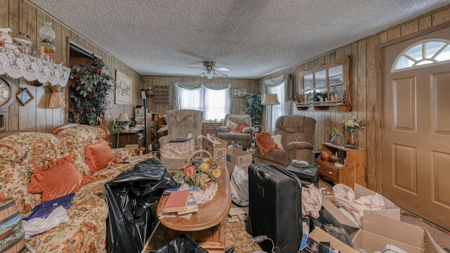 interior space with ceiling fan, wood walls, and a textured ceiling