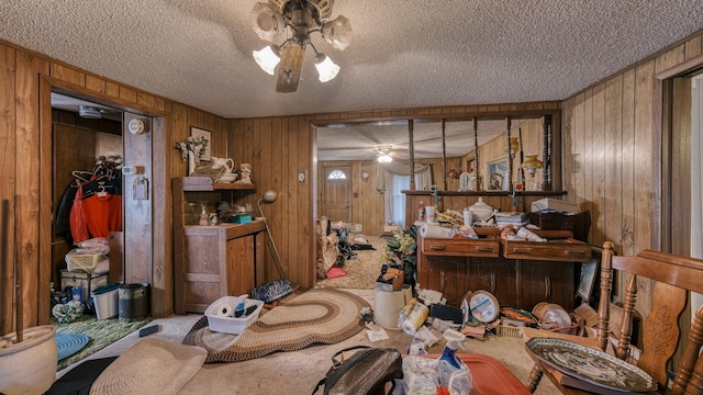 misc room with ceiling fan, wood walls, and a textured ceiling