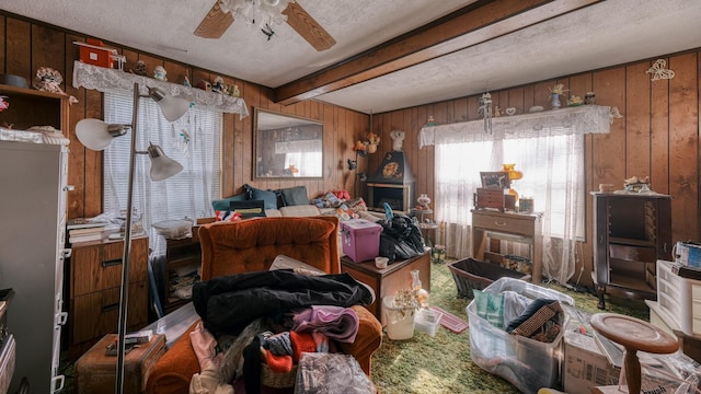 miscellaneous room with beamed ceiling, wood walls, and a textured ceiling