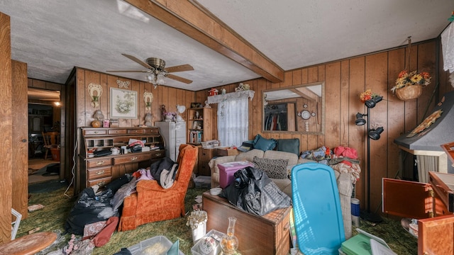 miscellaneous room featuring beam ceiling, wooden walls, ceiling fan, and a textured ceiling