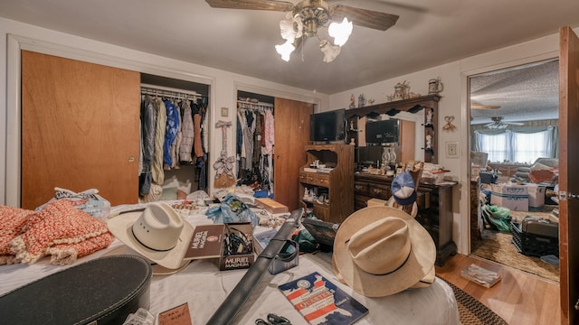 bedroom featuring hardwood / wood-style floors, ceiling fan, and two closets