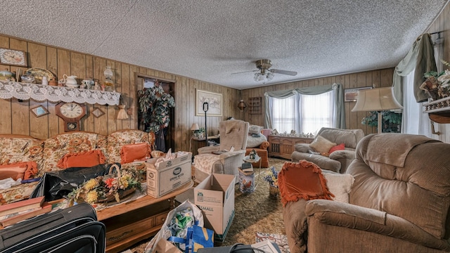 living room featuring ceiling fan, a textured ceiling, and wooden walls