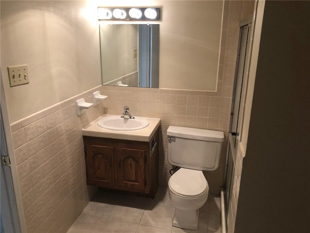 bathroom featuring tile patterned floors, vanity, toilet, and tile walls