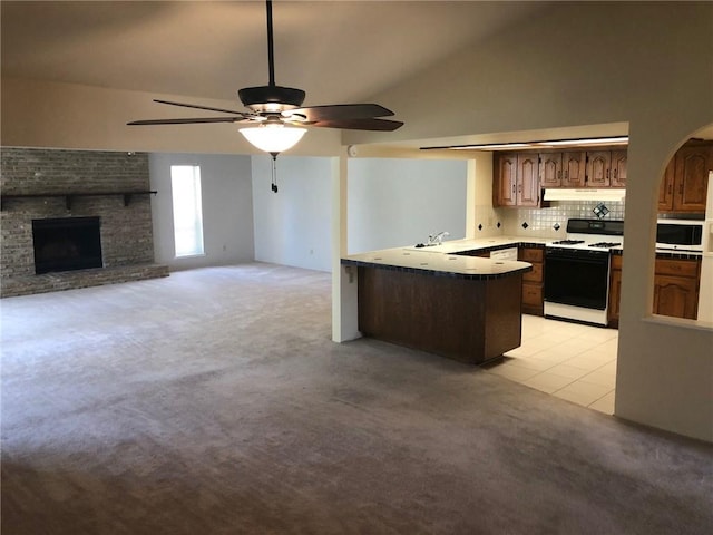 kitchen with ceiling fan, tasteful backsplash, range with gas cooktop, kitchen peninsula, and lofted ceiling