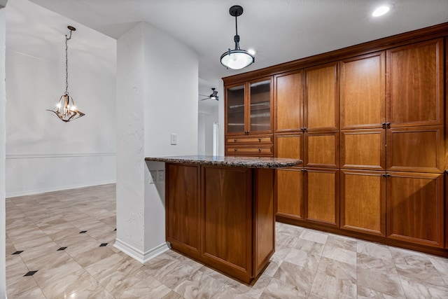 bar featuring ceiling fan, dark stone counters, and decorative light fixtures