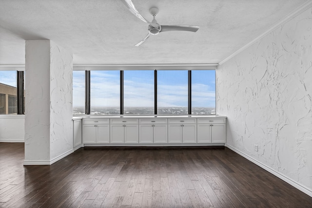 empty room featuring ceiling fan, crown molding, dark wood-type flooring, and a textured ceiling