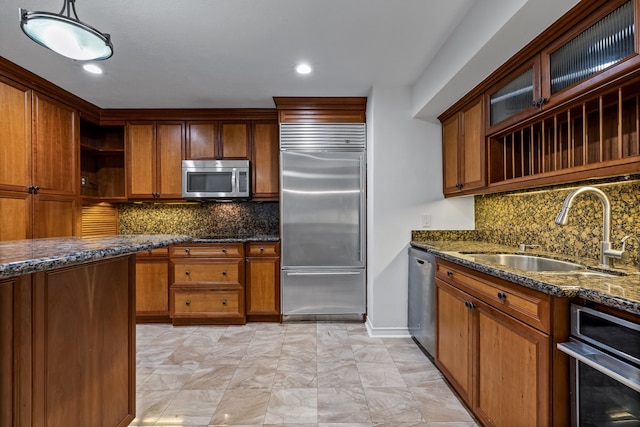 kitchen featuring appliances with stainless steel finishes, dark stone counters, pendant lighting, and sink